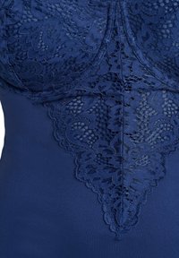 Marinblå bodysuit med en utsökt spetsöverlägg i blommönster över bröstet, med en mjuk och elastisk tyg under.