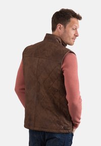 Brown leather vest with a diamond quilted pattern, high collar, and snap hardware, worn over a pink ribbed sweater. Back view shown.