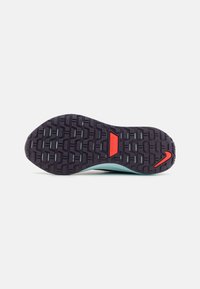 Nike bėgimo batų padas, turintis juodą gumos tread'ą su tekstūrizuotu raštu, akvamarino spalvos vidpadį ir raudoną akcentą ant kulno.