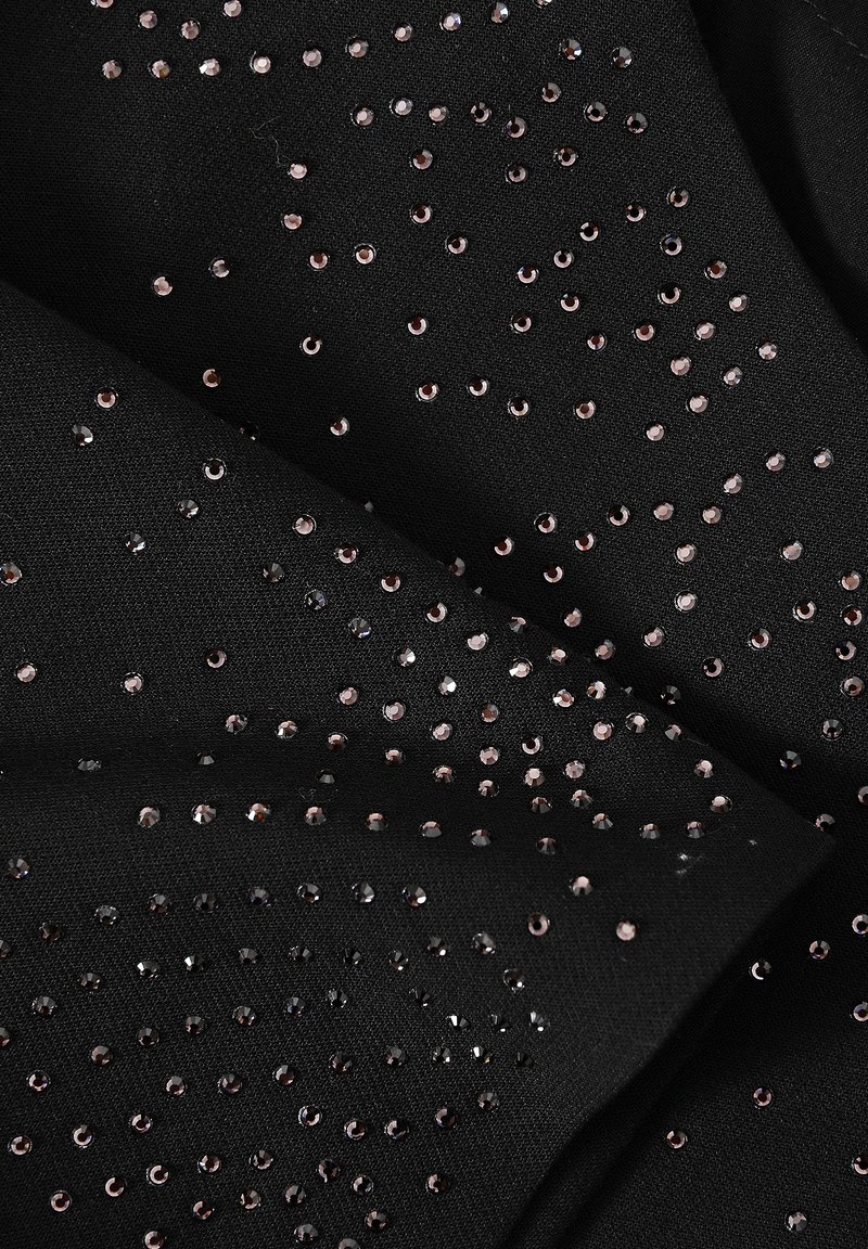 Czarna tkanina ozdobiona rozrzuconymi, odbijającymi światło różowo-złotymi cekinami o różnych rozmiarach, tworzącymi teksturową i wizualnie bogatą powierzchnię.