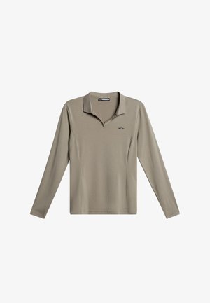 Koszula z długim rękawem i kołnierzykiem, wykonana z jasnobeżowej tkaniny o gładkiej fakturze, z małym czarnym logo na piersi.