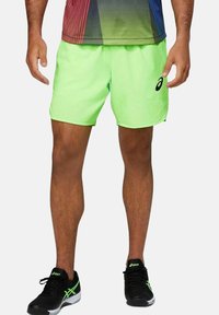 Shorts sportivi verde neon con vestibilità rilassata, texture liscia e logo Asics sul lato destro. Adatti per sport e attività ricreative.
