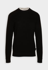 Schwarzer Strickpullover mit Rundhalsausschnitt und langen Ärmeln. Verfügt über eine strukturierte Oberfläche sowie gerippte Bündchen und Saum. Darunter ist ein weißer Stoff geschichtet.