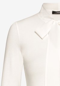 Weiße Bluse aus weichem Stoff mit einem Schleifenkragen, langen Ärmeln und glatter Textur. Ein subtiler Glanz hebt das Design hervor.