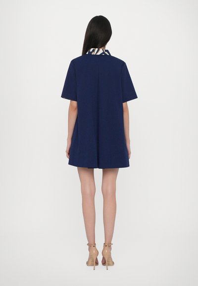 Abito blu navy a maniche corte con colletto a fantasia, vestibilità comoda e silhouette dritta, caratterizzato da una piega sul retro per maggiore libertà di movimento.