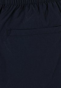 Tessuto blu navy con una finitura textured. Presenta una vita elasticizzata e una piccola tasca laterale con un dettaglio di cucitura.