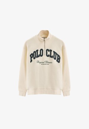 Cream-colored half-zip sweatshirt made of soft fabric. Features "POLO CLUB" and "Beyond Classics" printed in dark blue text across the chest.