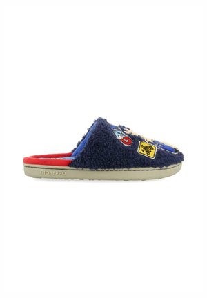 Pantofole fuzzy blu navy con una texture morbida, decorate con toppe colorate e un interno rosso a contrasto, poggiate su una suola chiara.