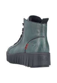 Bottine en cuir vert avec des lacets noirs, côté texturé, semelle en caoutchouc noir surélevée, et accent rouge près du logo à l'arrière.