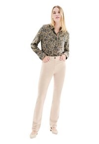 Chemise à manches longues à motifs avec un col, associée à un pantalon droit beige clair et des chaussures beiges. Les motifs comportent des teintes de bleu, vert et or.