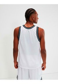 Camiseta sin mangas de baloncesto de malla blanca con detalles en negro y azul claro. Presenta un escote redondo y un diseño sin mangas. Vista trasera visible.