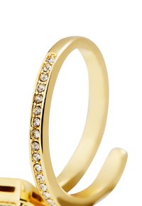 Anillo de oro con una banda delgada adornada con pequeñas piedras de circonio cúbico transparentes a lo largo de un lado. Acabado liso y pulido; diseño minimalista.