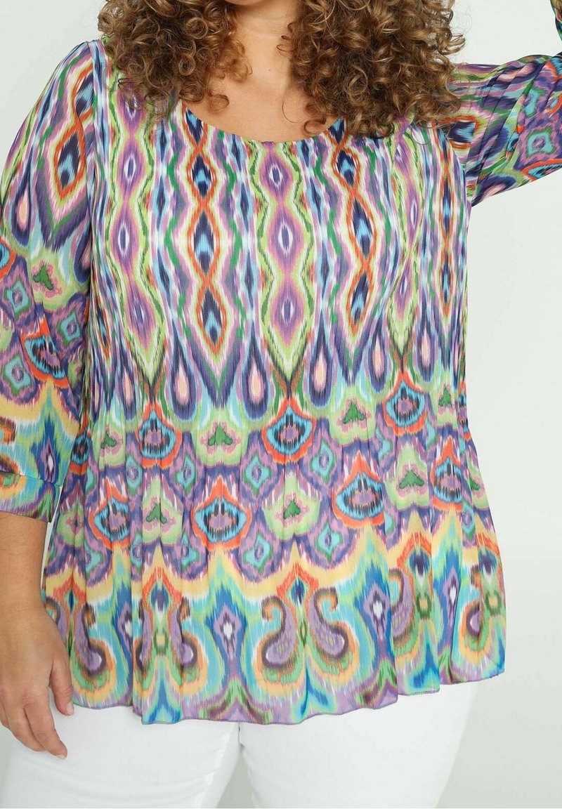 Blouse multicolore avec un design fluide, présentant un motif abstrait vibrant dans des tons de violet, vert et orange. Tissu doux et léger.
