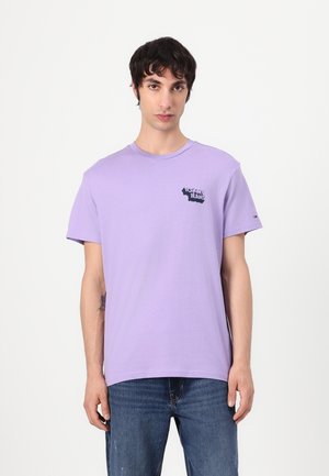 Lilacová bavlněná tričko s krátkým rukávem, které na levé hrudi zdobí černé logo "Tommy Jeans" a na rukávu je malé logo jako akcent.