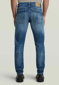 Slim fit jeans i medelblå denim med en blekt finish, som har två bakfickor, synlig sömnad och en märkespatch på midjan.