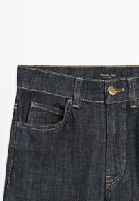Donkerblauwe denim jeans met voorzakken, riemlussen en een messing knoopsluiting, gelabeld Massimo Dutti, gemaakt in Turkije.