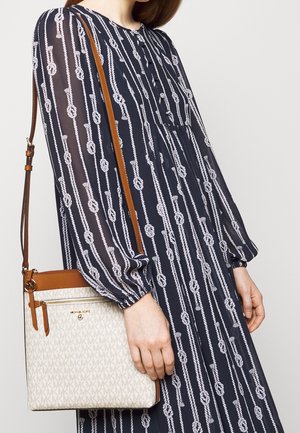 Marinekjole med hvidt rebprint, lange ærmer og knapdetalje, parret med en beige crossbody taske med monogrammønster og brune accenter.