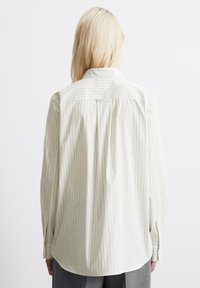 Light green and white striped long-sleeve shirt, featuring a classic collar and a pleated back detail, made from a smooth fabric.