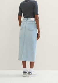 Ljusblå midjekjol i denim med två bakfickor och rak passform, kombinerad med en marinblå randig kortärmad topp och vita sneakers.