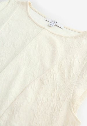 Haut sans manches de couleur crème avec des motifs texturés, un col rond et des détails cousus, étiqueté avec la marque "NEXT".
