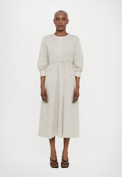 Gestreiftes Midi-Kleid aus leichtem Stoff mit rundem Ausschnitt und elastischem Bund. Mit Ballonärmeln und einem fließenden Schnitt, kombiniert mit schwarzen Sandalen.