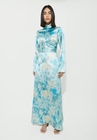 Abito a maniche lunghe, lungo fino al pavimento, realizzato in un morbido tessuto setoso che presenta un motivo tie-dye blu e beige con un dettaglio a torsione sul davanti.