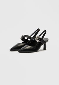 Μαύρα δερμάτινα παπούτσια slingback με μυτερά δάχτυλα και μικρό, τετράγωνο τακούνι. Διαθέτουν διασταυρωμένο λουράκι διακοσμημένο με μια διακοσμητική αγκράφα.