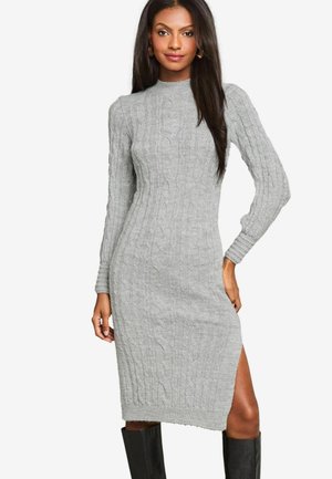 Gray cable-knit sweater dress with a high neckline, long sleeves, and side slits, complemented by knee-high black boots.