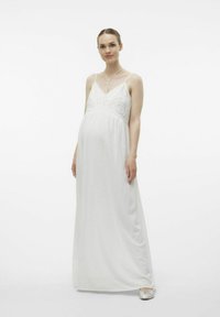 Robe de maternité blanche avec des détails en dentelle au niveau du corsage, bretelles spaghetti ajustables, silhouette fluide et tissu doux et texturé.