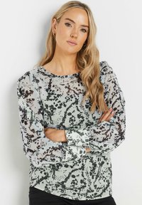 Blusa trasparente con una base verde chiaro, motivo astratto maculato nero, scollo rotondo e maniche lunghe a puff con polsini abbottonati.