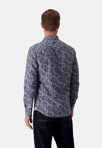 Camicia a maniche lunghe in tessuto stampato blu a motivi paisley. Presenta un colletto classico, polsini con bottone e un orlo curvo sul retro.