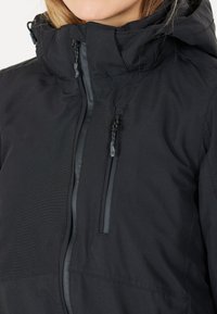 Schwarze wasserdichte Jacke mit hohem Kragen, Frontreißverschluss und Seitentaschen. Sie hat eine glatte Textur und ein elegantes Design.