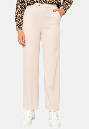Light beige wide-leg trousers with a smooth texture, side pockets, and a button closure, paired with white sneakers.