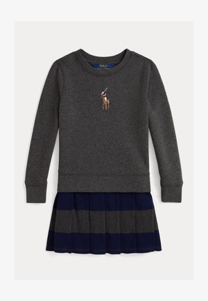 Siva dukserica s rebrastim manžetama, s logotipom igrača poloa. Uparena s plisiranom suknjom tamnoplave boje s sivim prugama.