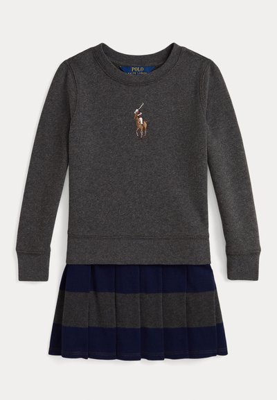 Sweatshirt cinza com punhos canelados, apresentando um logótipo de um jogador de polo. Combinado com uma saia plissada azul-marinho com riscas cinzas.