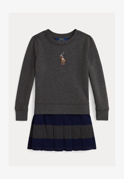 Sweatshirt cinza com punhos canelados, apresentando um logótipo de um jogador de polo. Combinado com uma saia plissada azul-marinho com riscas cinzas.