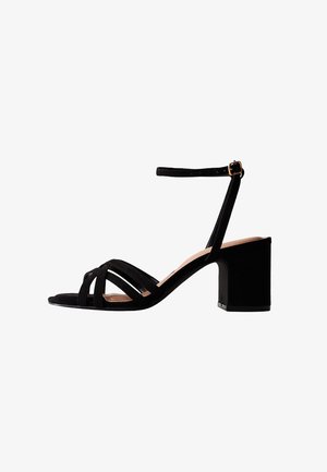 Sandalias de tacón cuadrado de ante negro con punta abierta, correa en el tobillo y múltiples tiras cruzadas en el empeine. Suela suave.