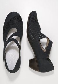 Scarpe in pelle nera perforata con dettagli in pizzo floreale e design a taglio. Presentano un tacco in legno scuro impilato e una cintura regolabile.