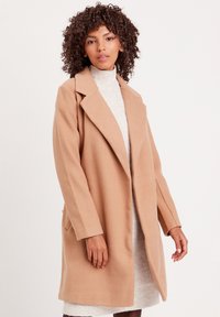 Beige Wollmischung Mantel mit Reverskragen, langen Ärmeln und seitlichen Taschen, verfügt über eine glatte Textur und ein knopflosem Design.