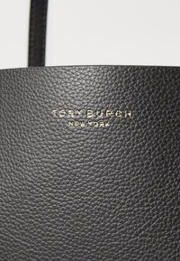 Zwarte leren tas met een gestructureerd oppervlak en een goudkleurig reliëflogo "TORY BURCH NEW YORK" die prominent op de voorkant is afgebeeld.