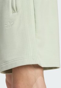 Heledane puuvillased lühikesed püksid pehme tekstuuriga, millel on tikitud logo ja küljeribad. Äär on õmmeldud vastupidavuse tagamiseks.