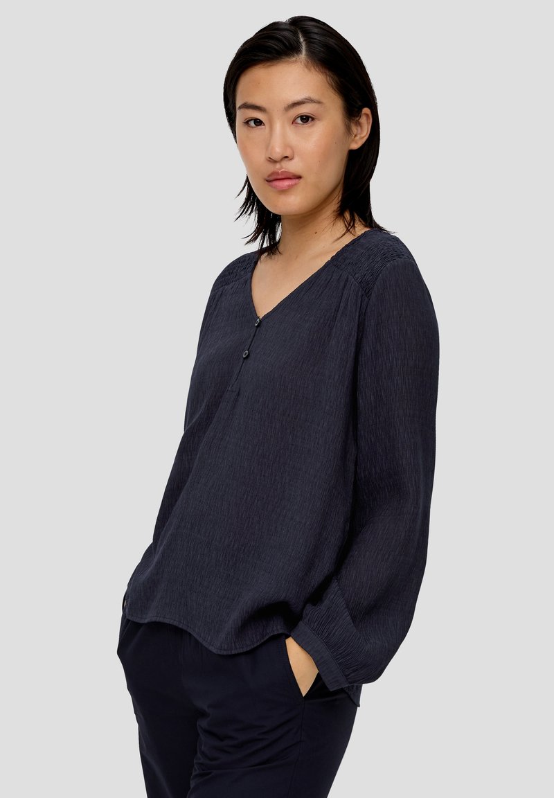 Marinebluse mit V-Ausschnitt, langen Ärmeln und Knopfdetail. Verfügt über strukturierten Stoff und eine lockere Passform mit seitlichen Taschen.