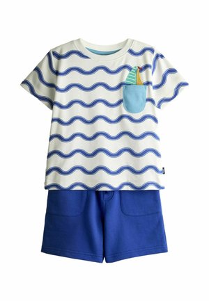 Detský outfit pozostávajúci z bielej trička s krátkym rukávom s modrými vlnkovými pruhmi a plachetnicou na náprsnej vrecku, v kombinácii s jednofarebnými modrými šortkami.