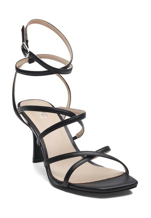 Sandale noire à brides fines, avec un bout carré, des lanières élancées et un talon bloc moyen. Texture lisse et design minimaliste.