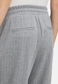 Szare spodnie w paski z elastycznym paskiem w talii, z dyskretnymi kieszeniami z tyłu i miękką teksturowaną tkaniną.
