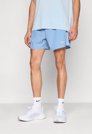 Shorts de sport bleu clair avec un logo Nike noir, accompagnés de baskets blanches et de chaussettes de sport blanches avec un logo noir.