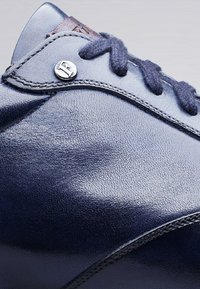 Chaussures en cuir bleu marine avec une surface texturée, un bout rond, des lacets foncés contrastants et un accent métallique près de l'œillet pour un détail supplémentaire.