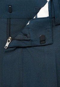 Dunkelblaues Gewebe mit einer strukturierten Webart, das einen silbernen Reißverschluss und einen schwarzen Hakenverschluss aufweist. Das Innere zeigt ein kontrastierendes weißes Muster.