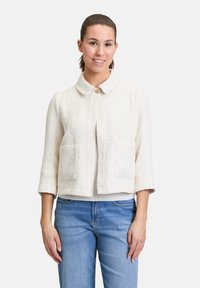 Crème-kleurige cropped jack met een kraag, driekwartmouwen, twee voorzakken en een gestructureerde afwerking. Knopsluitingdetal.