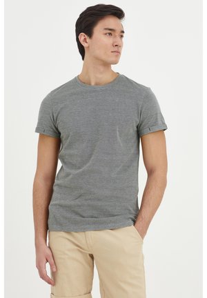 Szary t-shirt z krótkim rękawem i okrągłym dekoltem, z podwiniętymi mankietami, wykonany z miękkiego, teksturowanego materiału. Noszony z beżowymi szortami cargo.